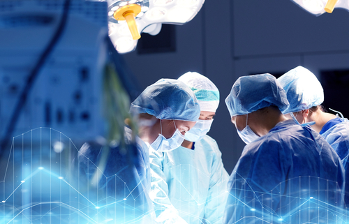 Picture of a Surgeon Team in an Operation Room fully covered in medical attire. There is four of them standing around the operation table.